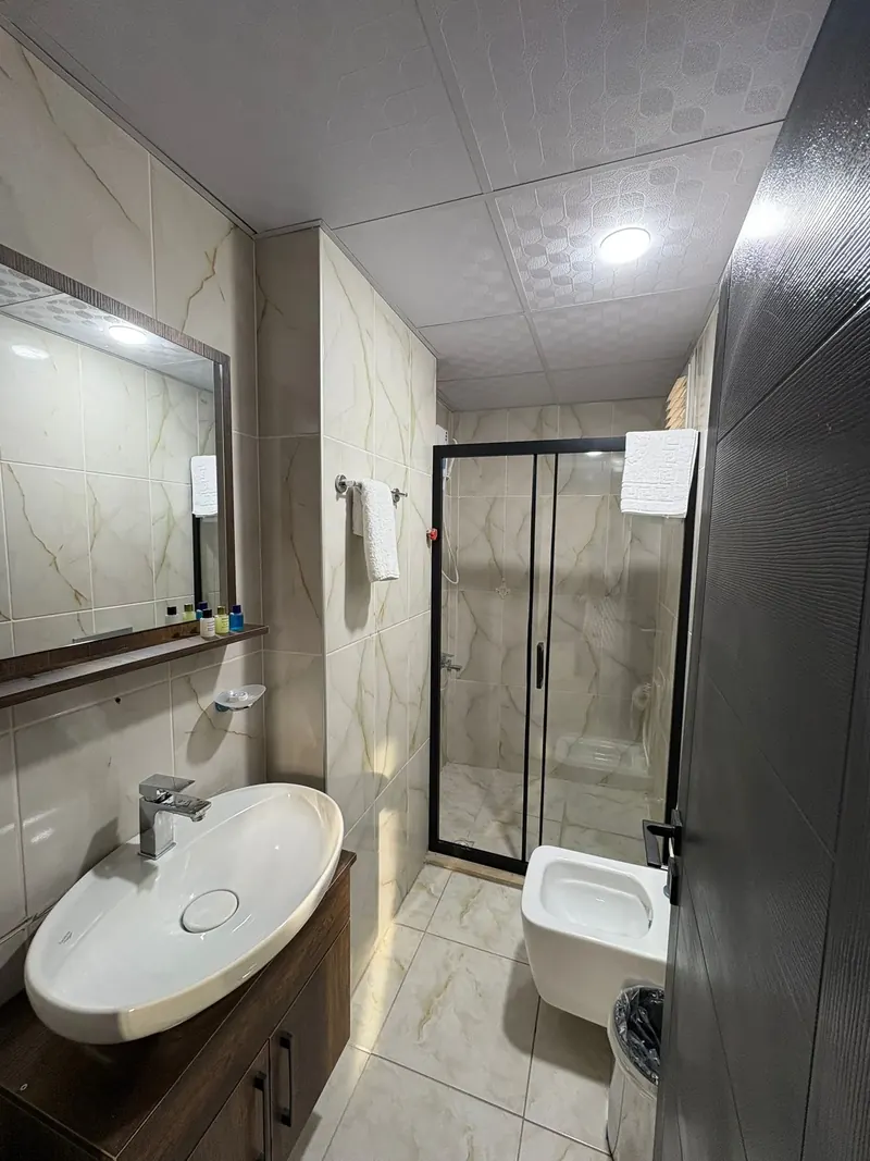 Banyo: lavabo, ayna, duşakabin ve mermer desenli seramik